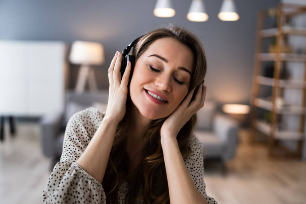 Smiling Woman Listening Music Using Headphones In Living Room - Photo, Image