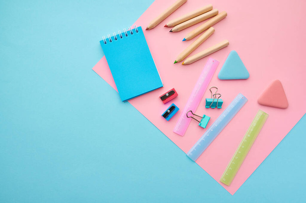 Office stationery supplies, blue and pink background. School or education accessories, writing and drawing tools, pencils and rubbers, ruler and paper clips - Photo, image