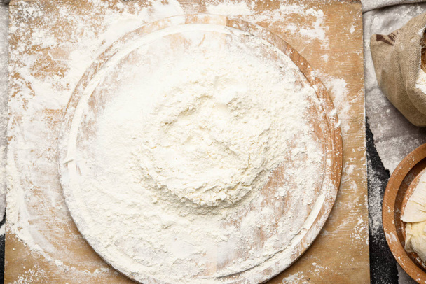 white wheat flour heaped on a round wooden board, top view - Photo, image