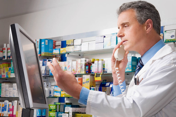 mužský lékárník s lahvičkami léku v lékárně - Fotografie, Obrázek