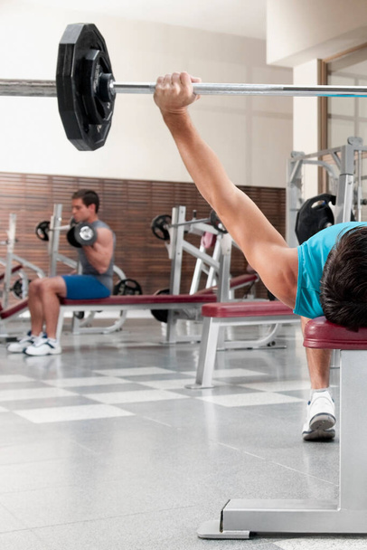 young man working out with dumbbells in gym - Foto, immagini