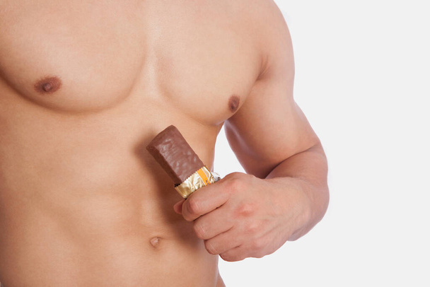 muscular man with naked torso and a bottle of coffee on a white background - Foto, Imagen