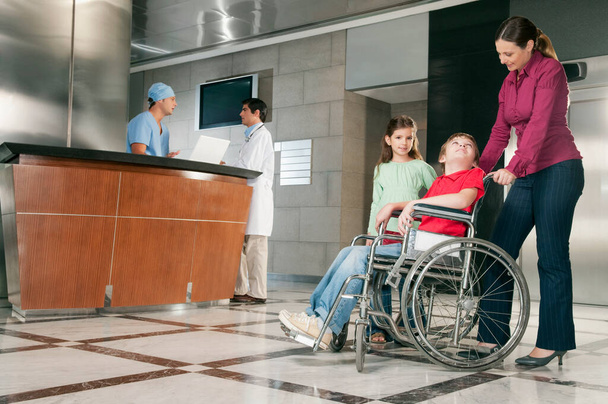 homme handicapé et femme en fauteuil roulant avec son fils à l'hôpital - Photo, image