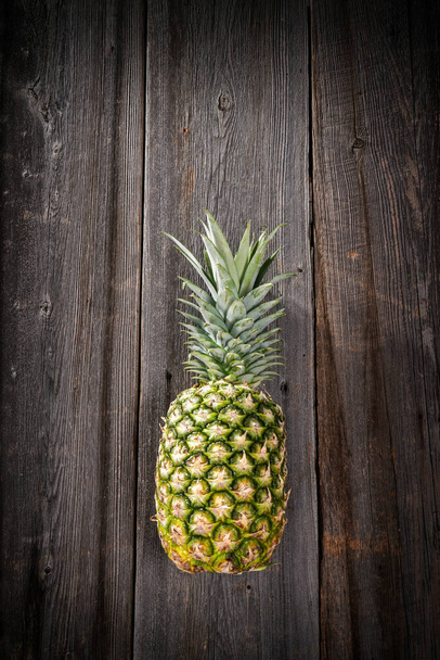 Big tropical pineapple with its leaves on a barn wood board - Foto, imagen