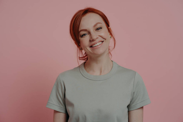 Positive relaxed redhead woman with pleasant appearance smiling cheerfully, isolated on pink - Foto, afbeelding