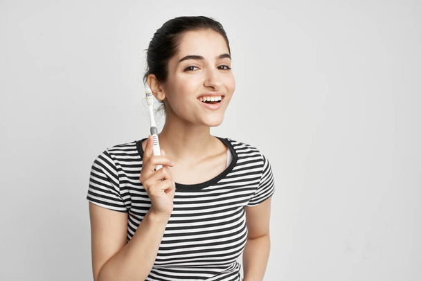 mujer alegre cepillarse los dientes higiene fondo claro - Foto, Imagen