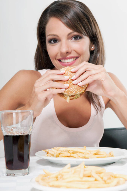 young woman eating burger and looking at camera - Foto, Imagen