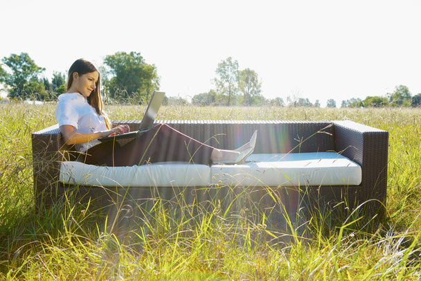 young woman sitting on the grass and using laptop - Foto, Imagem