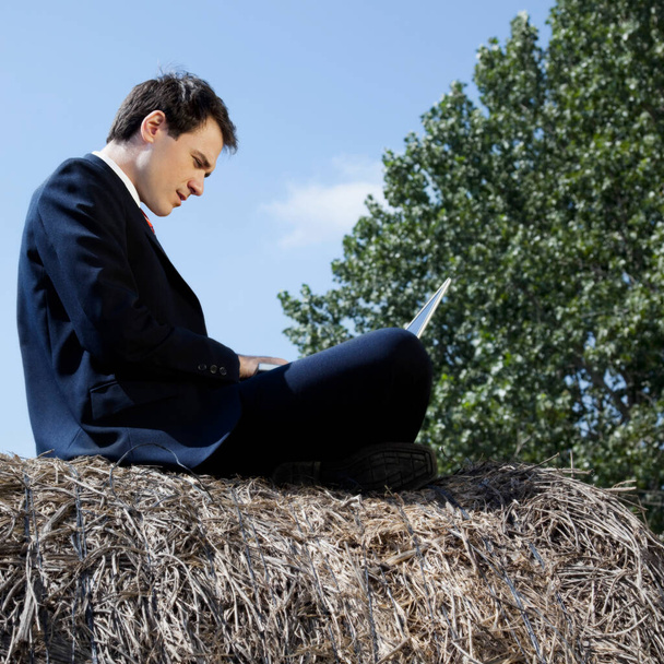 young man with a laptop on the background of the field - Foto, imagen