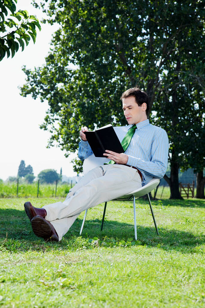 young man sitting on bench and reading book - Photo, image
