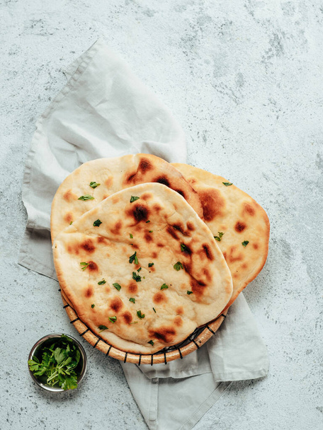 Fresh naan bread on gray cement background with copy space. Top view of several perfect naan flatbreads. Vertical - Фото, изображение
