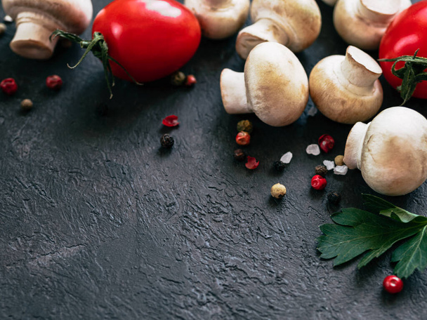 Food ingredients on black background, copy space Mini champignons, cherry tomatoes, herbs and spices top view or flat lay - 写真・画像