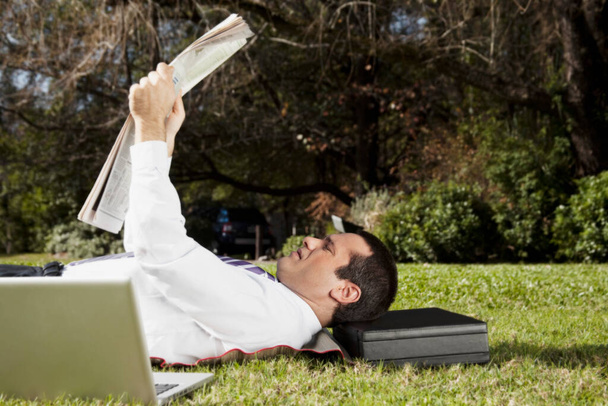young man lying on grass and reading book - Foto, Imagem