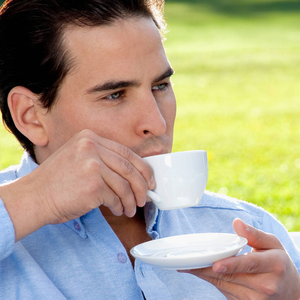 young man drinking coffee in the park - Zdjęcie, obraz