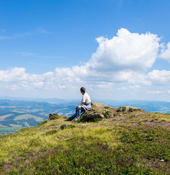 Чоловік сидить і дивиться на гори
 - Фото, зображення