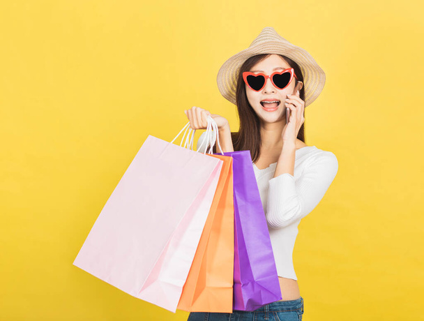 happy young woman holding shopping bags and talking on mobile phone - Φωτογραφία, εικόνα