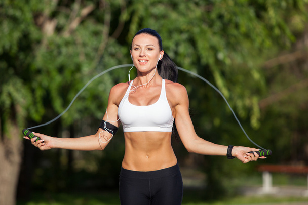 A sportive beautiful woman in a park with a rope - Foto, imagen