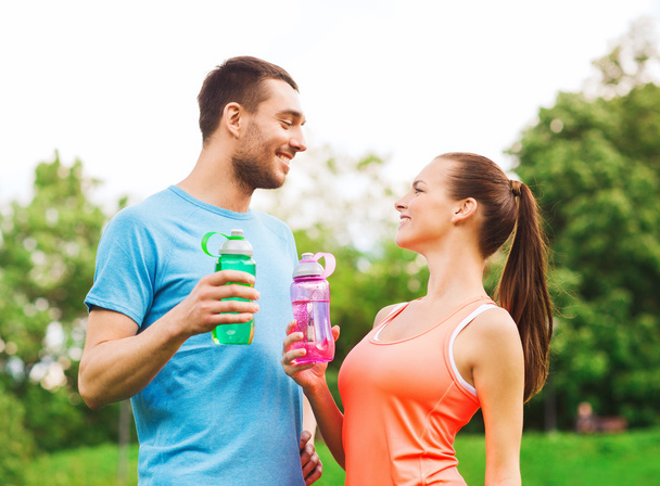 smiling couple with bottles of water outdoors - Foto, Bild