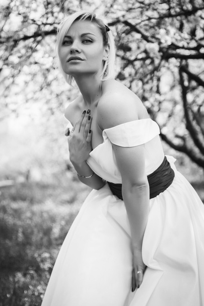 Blonde in white dress in the spring garden - Foto, imagen