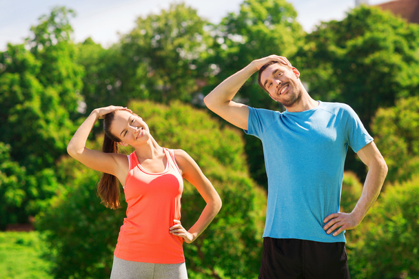 smiling couple stretching outdoors - 写真・画像