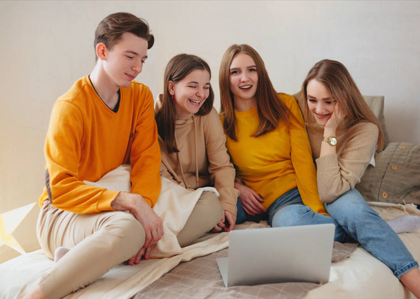Happy teenage friends watching funny content on laptop and laughing - Фото, зображення