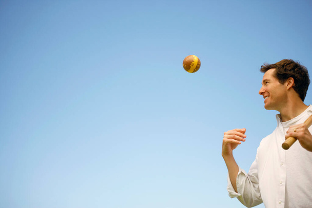 Low angle view of a mid adult man tossing a ball - Foto, imagen