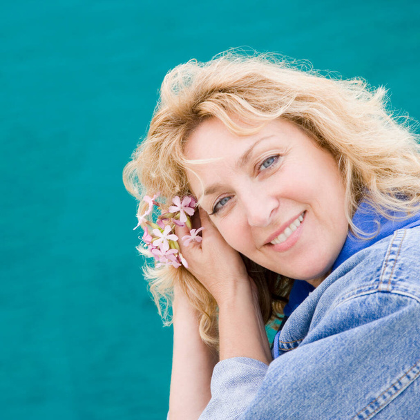 portrait of a beautiful blonde woman in a blue dress on a background of a lake - Fotografie, Obrázek