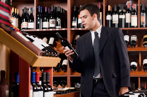 young man holding bottle of wine in the bar - Photo, Image