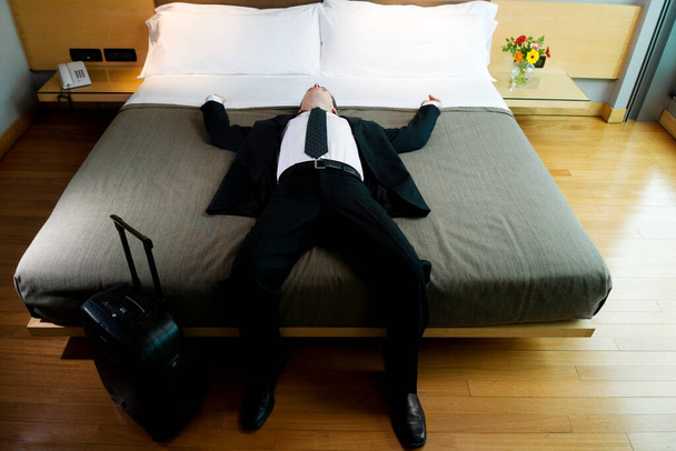 man lying on bed with a suitcase - Фото, зображення