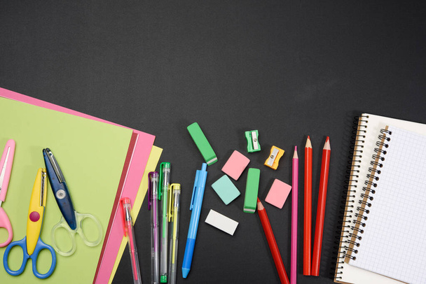 colorful wooden pencils, notepads on a blank black chalk board, school stationery, copy space, back to school - Foto, Imagen