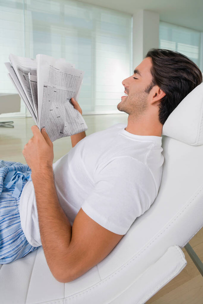 man reading newspaper on sofa - Foto, afbeelding