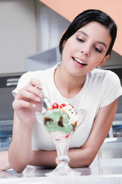 young woman eating ice cream in the kitchen - 写真・画像