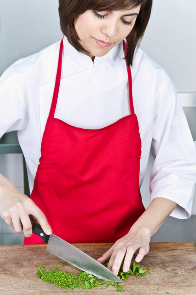 young woman chef cooking with red pepper, closeup - 写真・画像