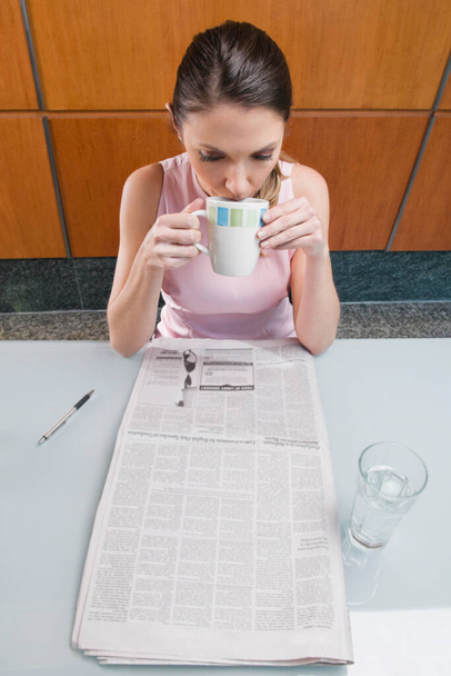High angle view of a businesswoman drinking coffee and reading a newspaper - Foto, Imagem