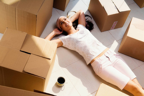 young woman unpacking boxes with cardboard box - Fotó, kép