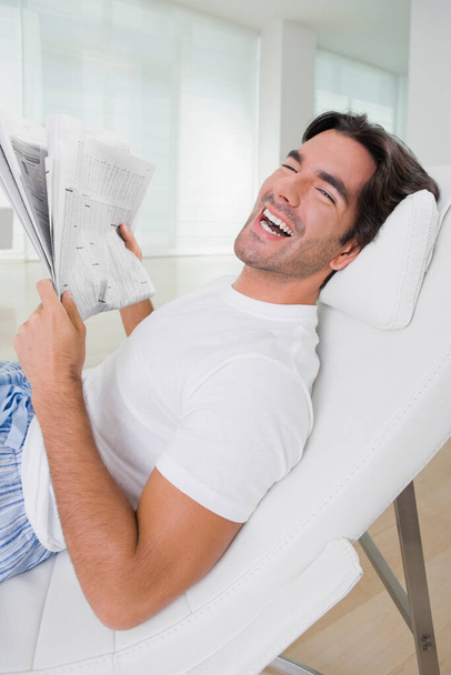 νεαρός άνδρας διαβάζει εφημερίδα στο σαλόνι - Φωτογραφία, εικόνα
