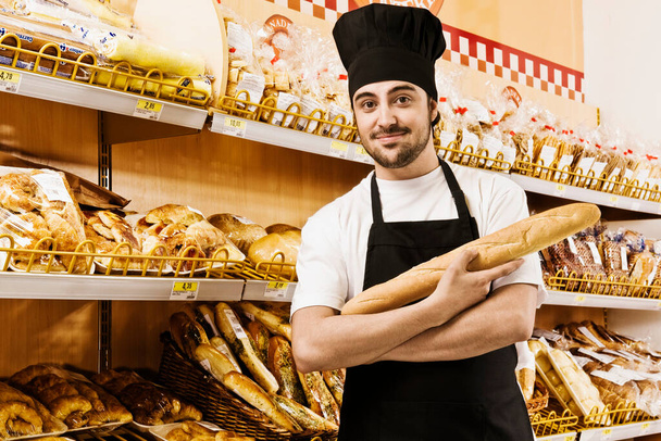 baker with a variety of bread in the bakery - Valokuva, kuva