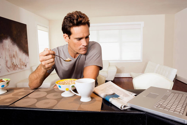young man with cup of coffee and laptop at home - Foto, Imagen