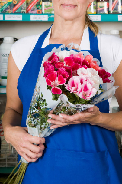 beautiful florist holding a bouquet of fresh flowers in a flower shop - Photo, image