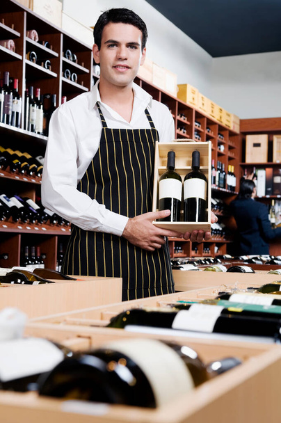 young man in apron holding wine bottles in a restaurant - Foto, Bild