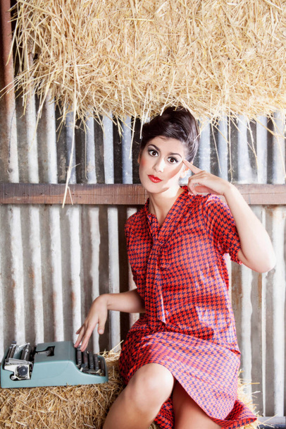 beautiful young woman in a straw hat and a plaid shirt on a background of hay - Foto, afbeelding