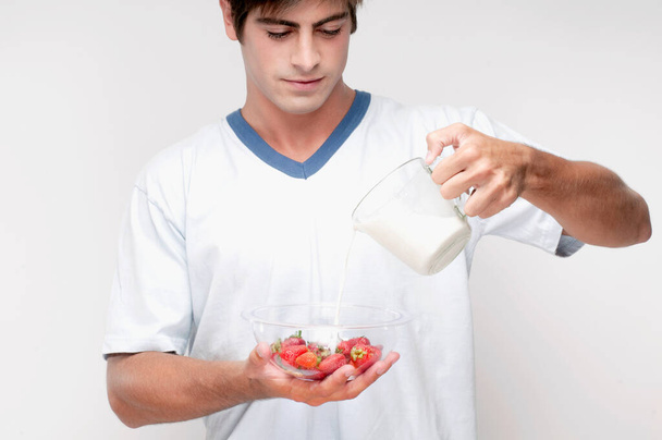 Mann mit einer Flasche Milch und einem Glas Wasser auf weißem Hintergrund - Foto, Bild