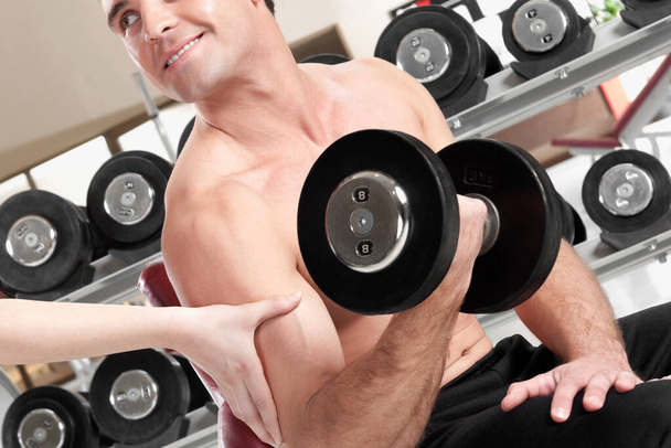 young man lifting weights in gym - Fotó, kép