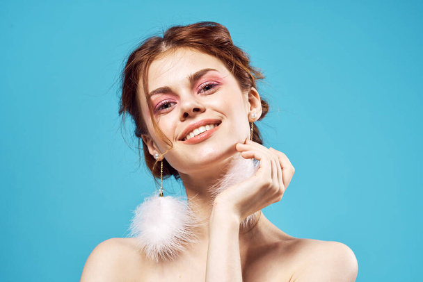 fröhliche Frau nackte Schultern und flauschige Ohrringe helles Make-up posiert - Foto, Bild