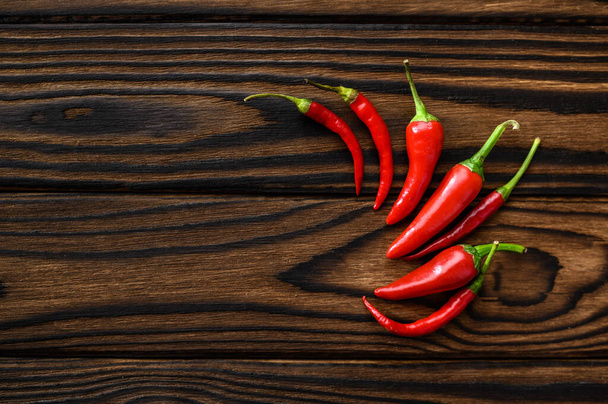 Fragrant red pepper isolated on wooden background, top view. Organic vegetarian food, grocery assortment, natural eco products, healthy lifestyle concept - Photo, image