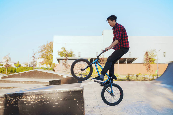 Young bmx biker doing trick, training in skatepark. Extreme bicycle sport, dangerous cycle exercise, risk street riding, biking in summer park - Foto, immagini