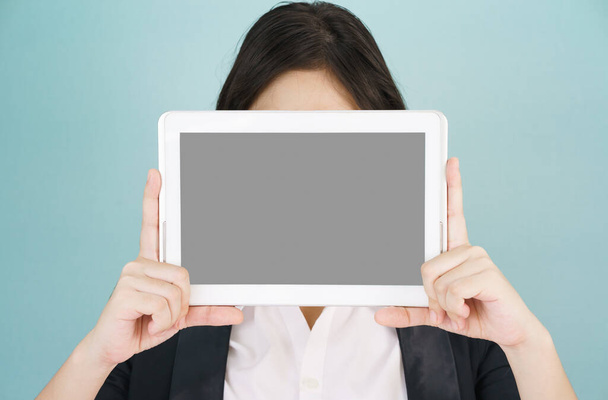 Young asian women in suit holding her digital tablet standing against green background - Photo, image
