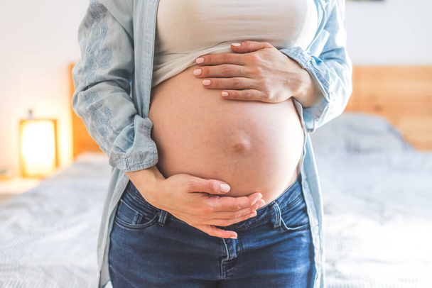 Caucasian pregnant mother touching her naked tummy, blue jeans, close up - Valokuva, kuva