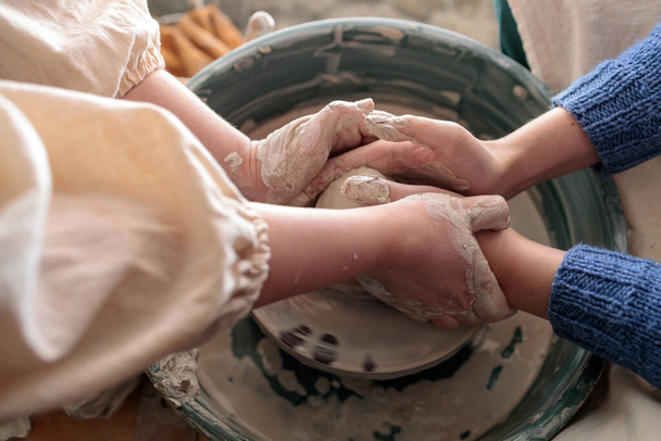 a mentor teaches a young potter. hands control the hands of another. training on creating clay products. production of pottery - Foto, immagini
