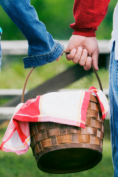 Close-up of two people carrying a picnic basket - Fotó, kép